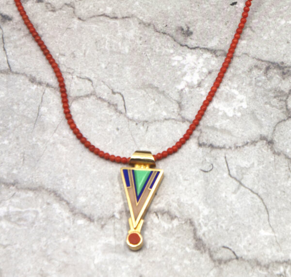 A necklace with a triangle and red bead on it.