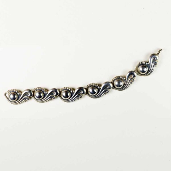 A silver bracelet with some small balls on it