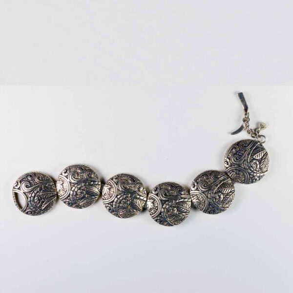 A silver bracelet with seven circles of metal.