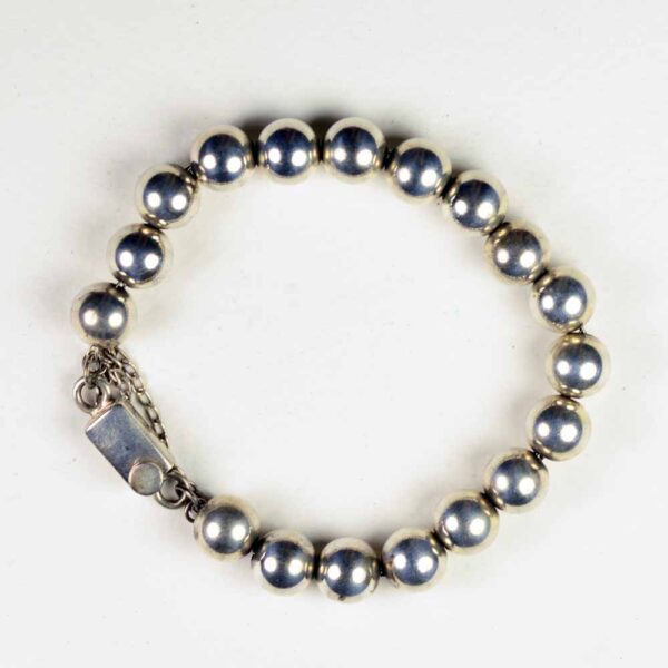 A silver bracelet with a chain and beads.