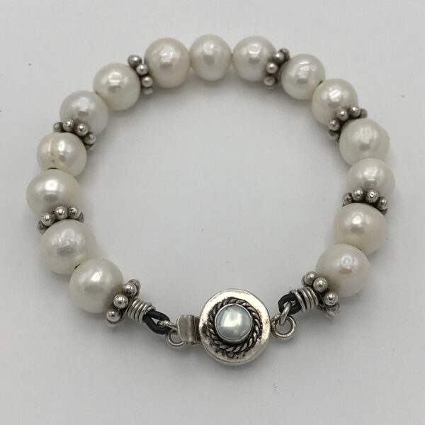 A bracelet with pearls and silver beads on it.