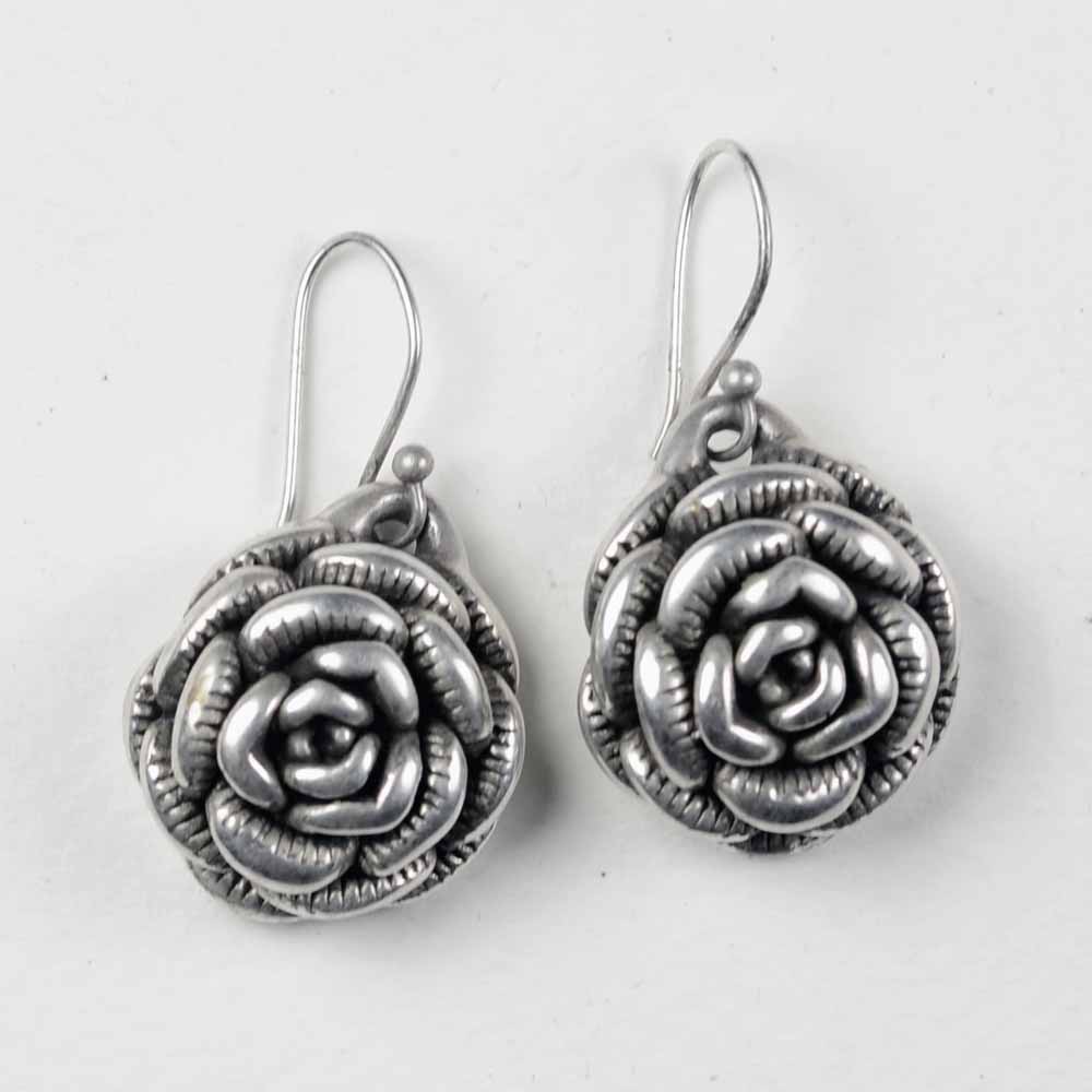 A pair of silver earrings with a rose design.