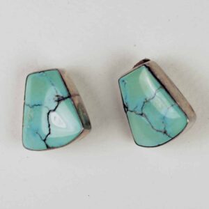 A pair of turquoise earrings sitting on top of a table.