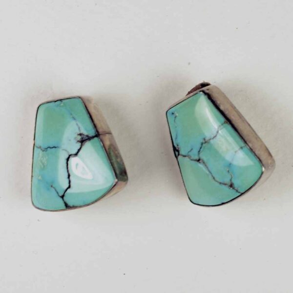 A pair of turquoise earrings sitting on top of a table.