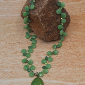 A green necklace sitting on top of a wooden table.