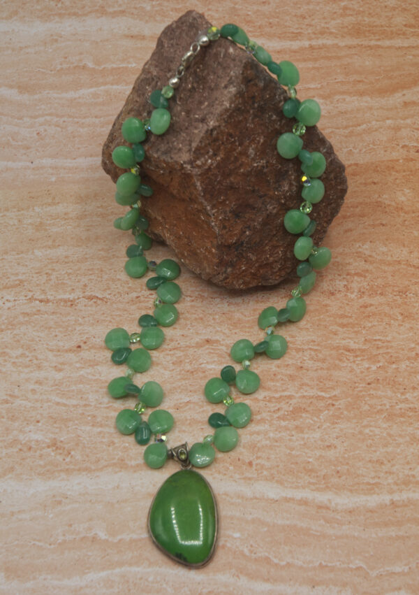 A green necklace sitting on top of a wooden table.