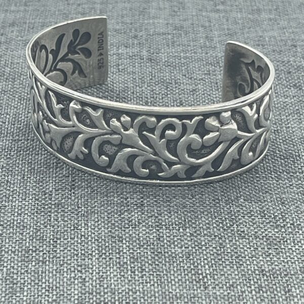 A silver bracelet with a leaf design on it.