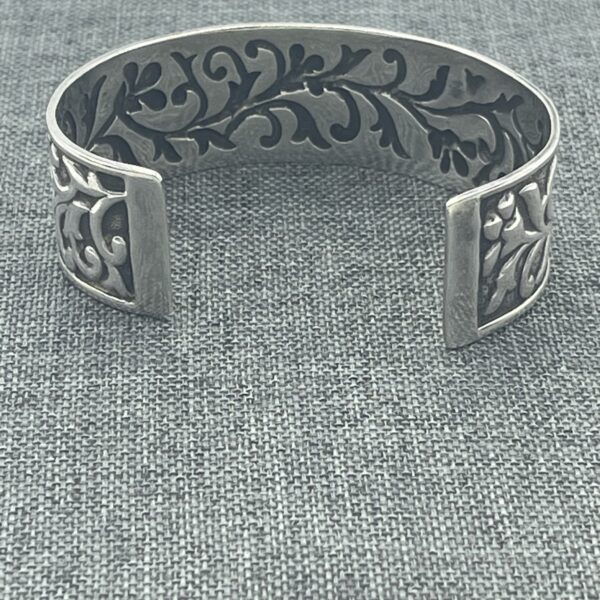 A silver bracelet with a black design on it