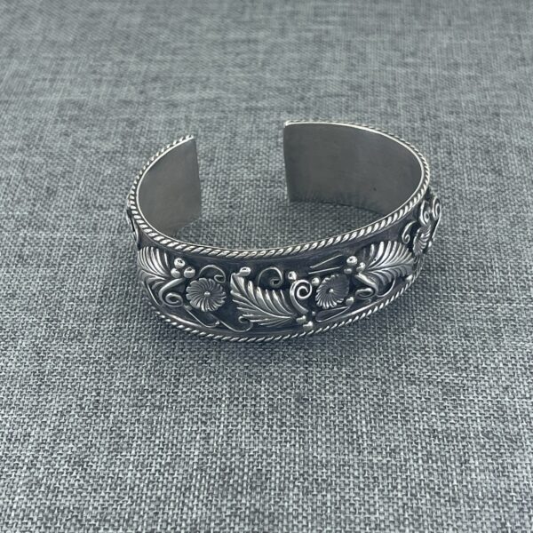 A silver bracelet with some flowers on it