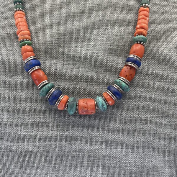 A necklace of orange and blue beads on a gray background.