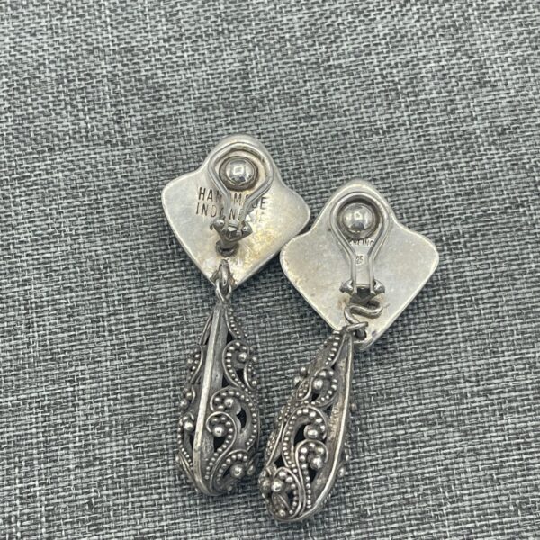 A pair of silver earrings with a decorative design.