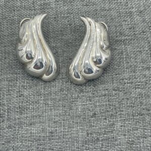 A pair of silver earrings on top of a gray cloth.