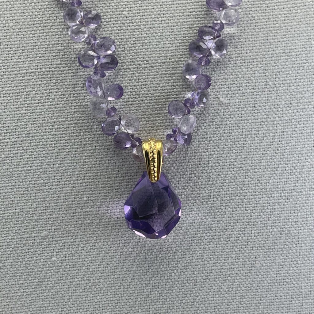 A necklace with purple beads and a large crystal pendant.