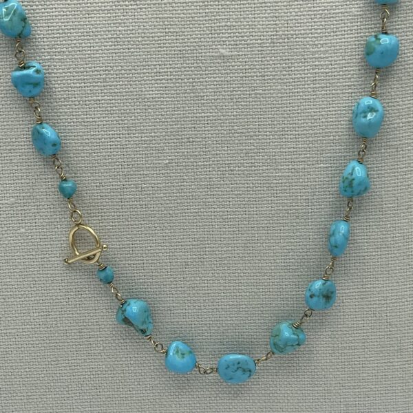 A necklace with blue beads and gold chain.