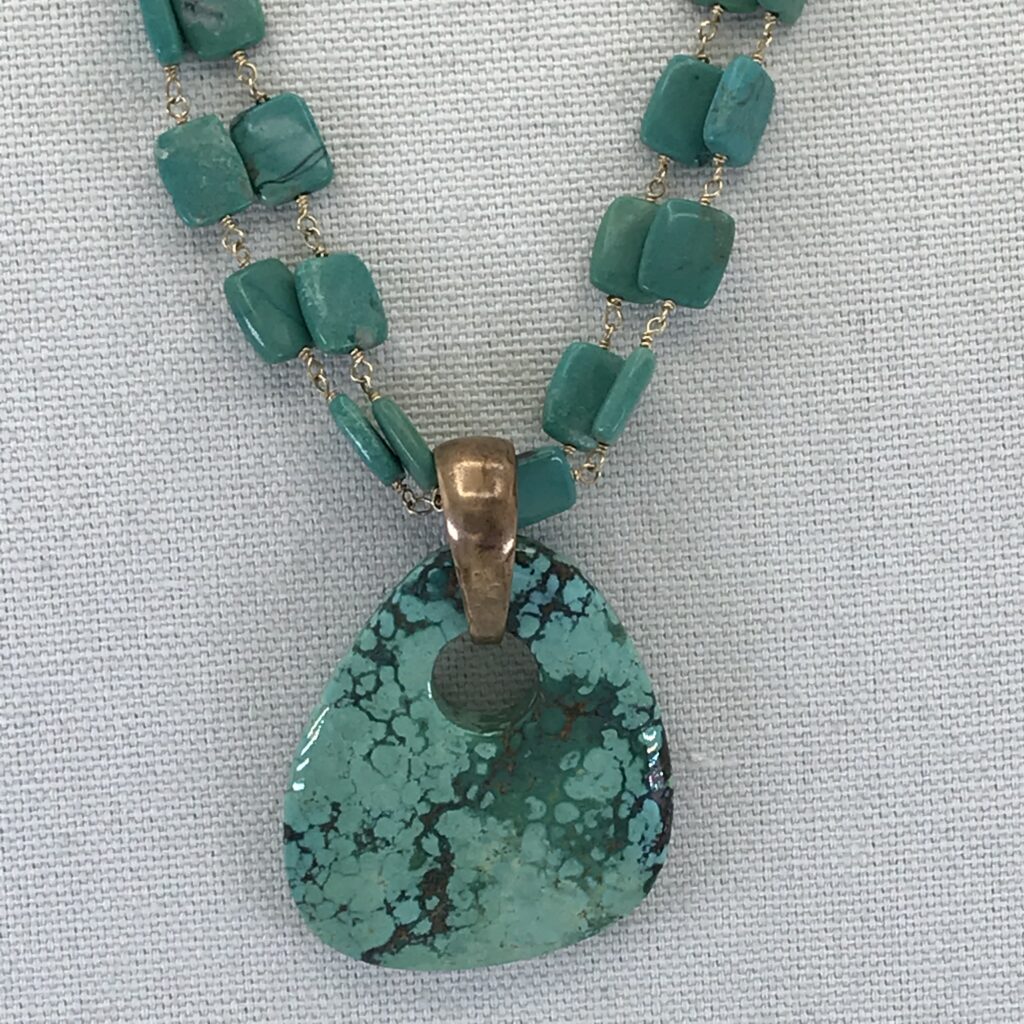 A necklace with a turquoise pendant on it.