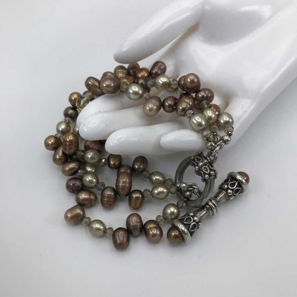 A hand is holding a rosary with pearls.