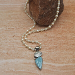 A necklace with pearls and a blue stone.