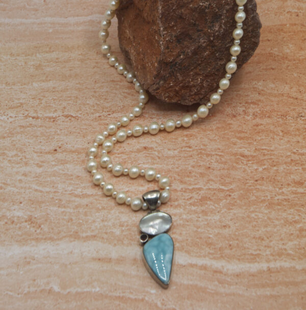 A necklace with pearls and a blue stone.