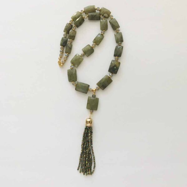 A long necklace with green stones and gold tassels.