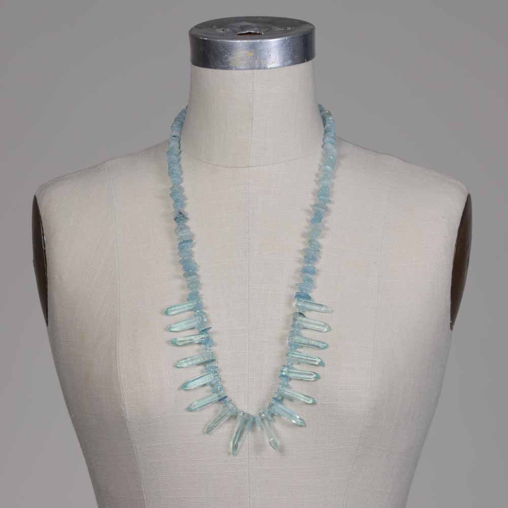 A mannequin wearing a necklace with blue beads.