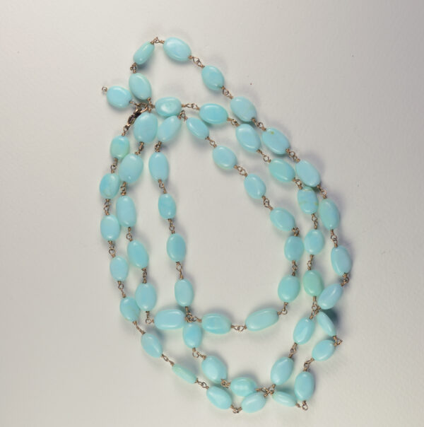 A long necklace of blue beads on a white background