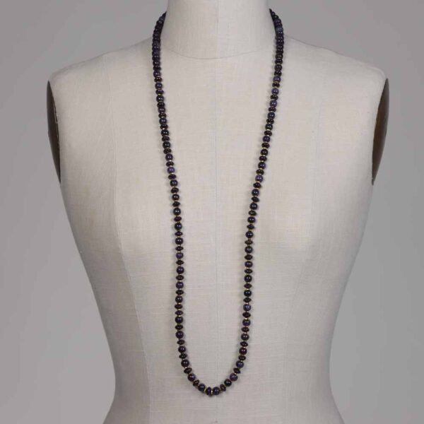 A mannequin wearing a long necklace of black beads.