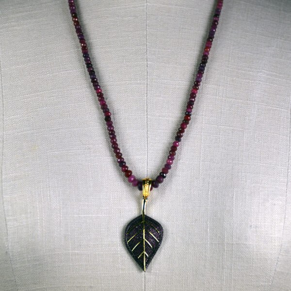 A necklace with a leaf pendant and beads.