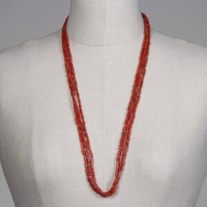 A mannequin wearing a long necklace of red beads.