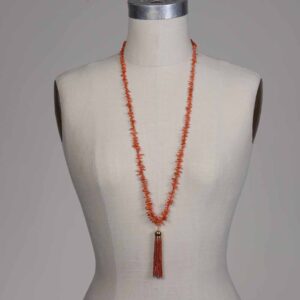 A woman wearing an orange necklace with a tassel.