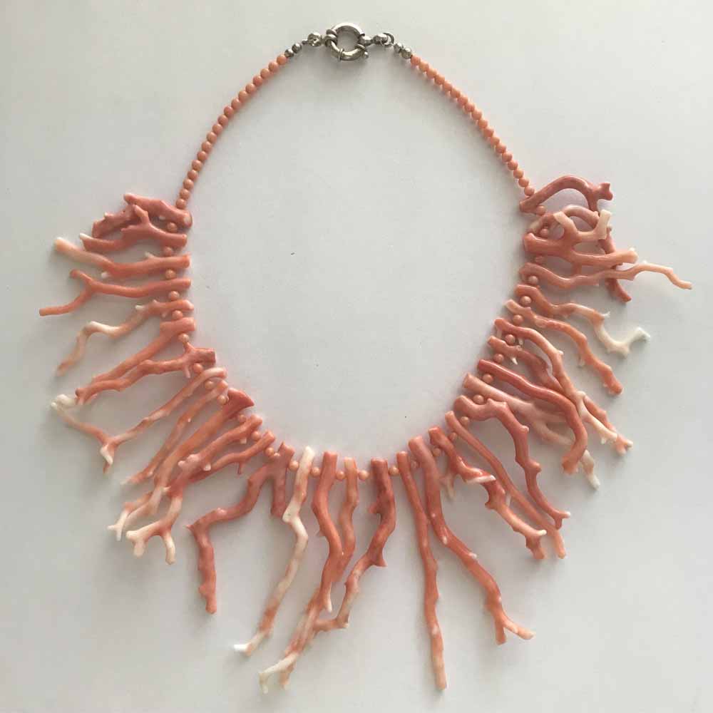 A necklace made of coral and a metal ring.