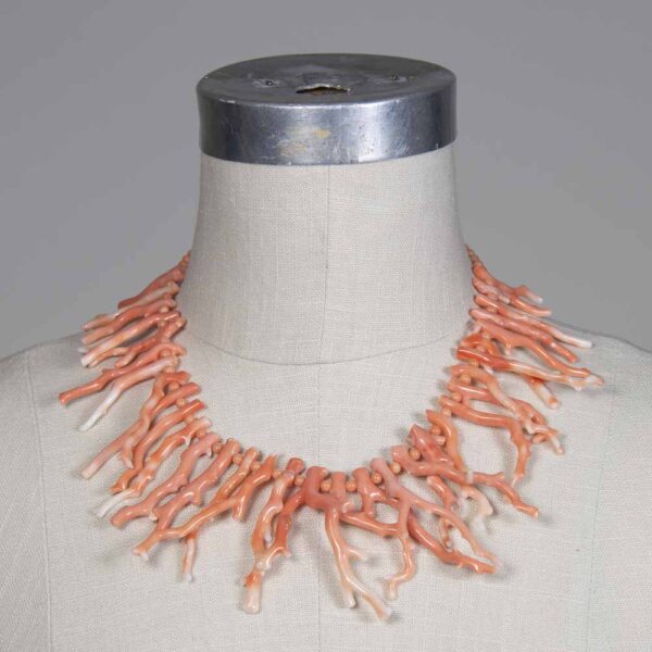 A mannequin wearing a necklace with coral.