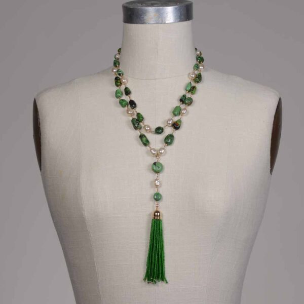 A woman wearing a necklace with green beads and tassels.