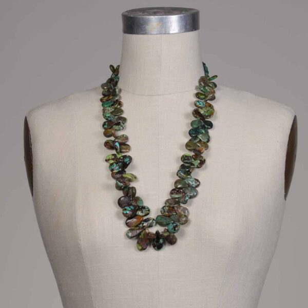 A mannequin wearing a necklace with green and brown beads.