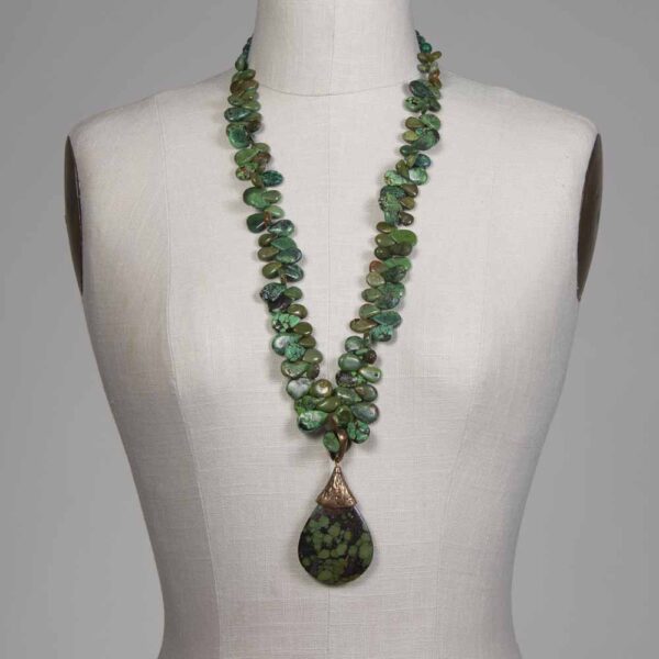 A necklace with green beads and a large pendant.