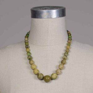 A necklace of green and yellow beads on display.