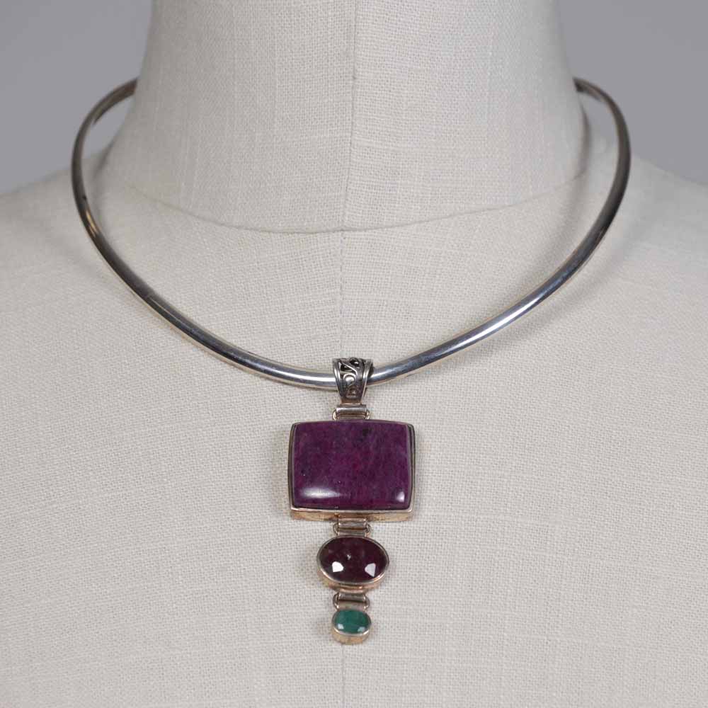 A necklace with a purple stone and green bead.