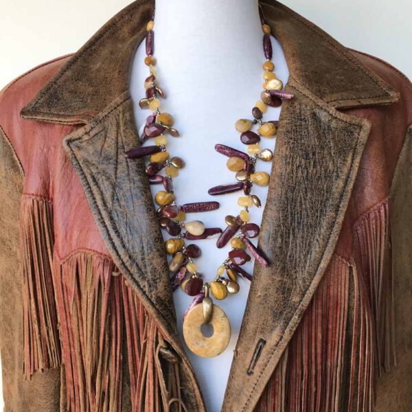 A brown leather jacket with a necklace and earrings.