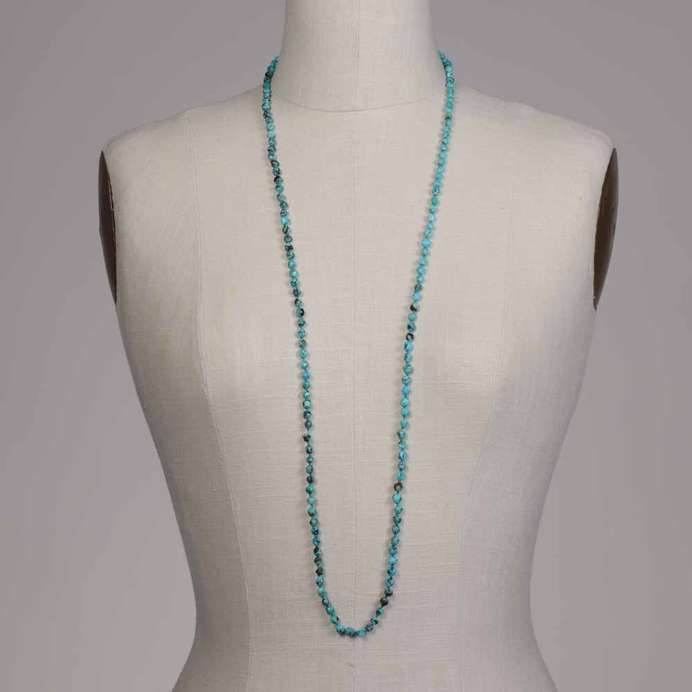 A mannequin wearing a necklace of turquoise beads.