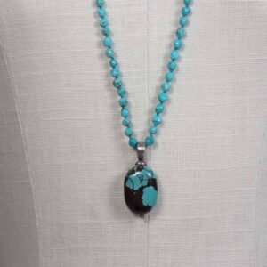 A necklace with turquoise beads and a black stone.