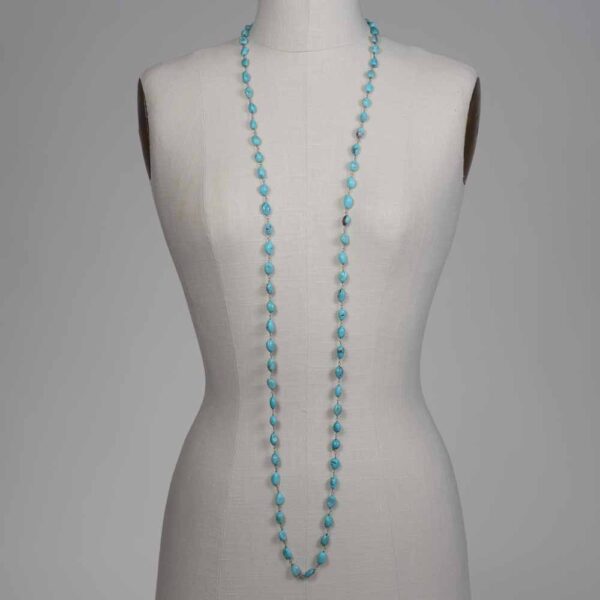 A mannequin wearing a necklace with blue beads.