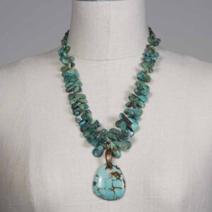 A necklace with turquoise and green beads on a mannequin.