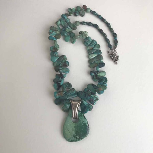 A necklace with green beads and a large pendant.