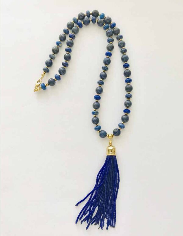 A blue tassel necklace sitting on top of a white table.