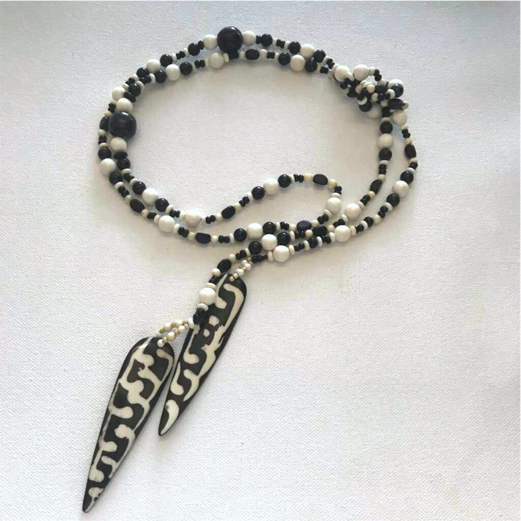 A necklace with black and white beads, and two feathers.