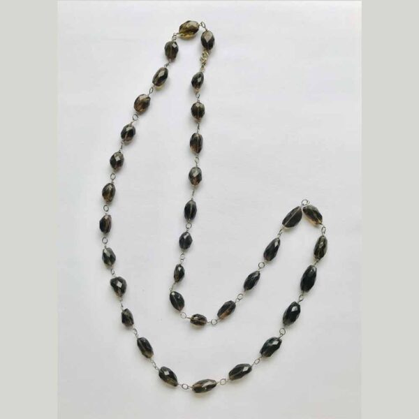 A long necklace of black beads on a white background