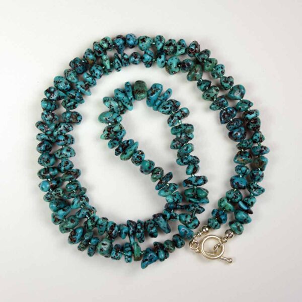 A long necklace of turquoise beads and silver clasp.