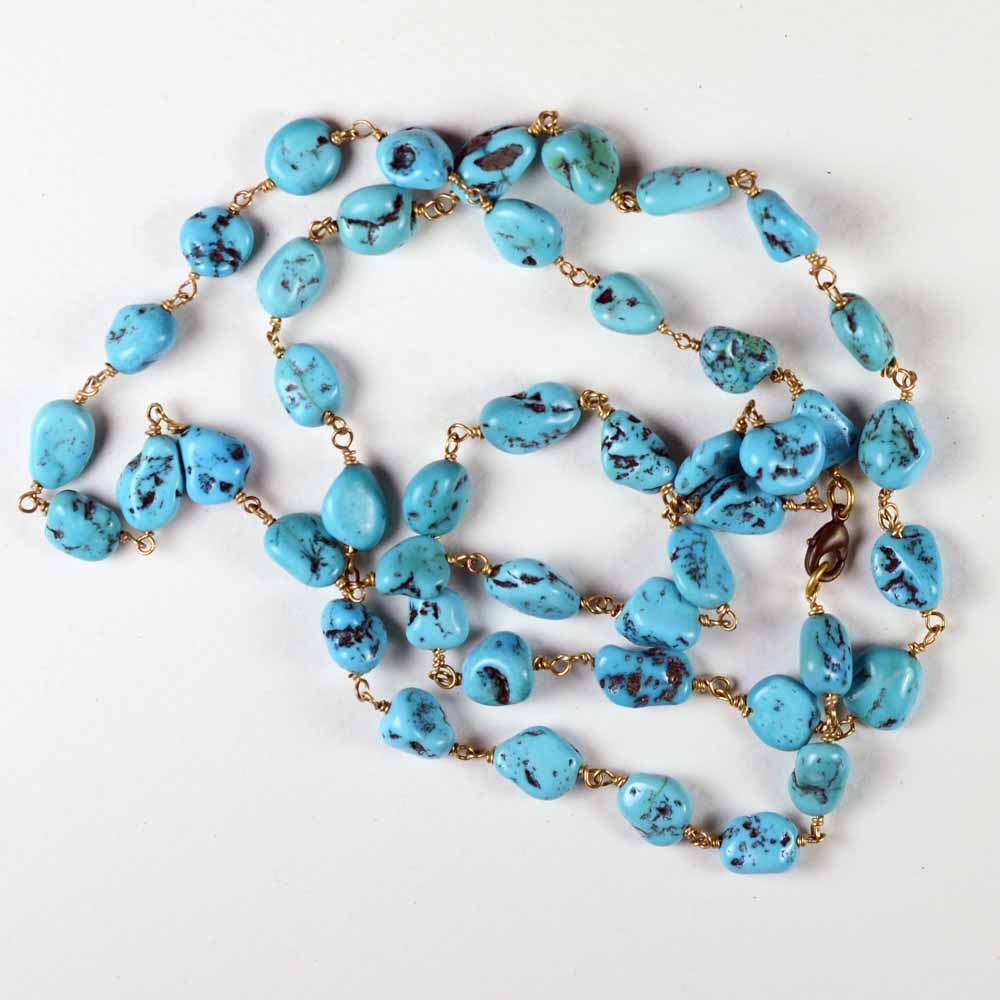 A long necklace of turquoise beads on a white background