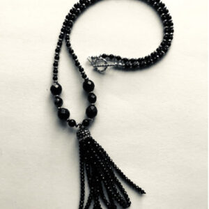 A black beaded necklace with a silver tassel.