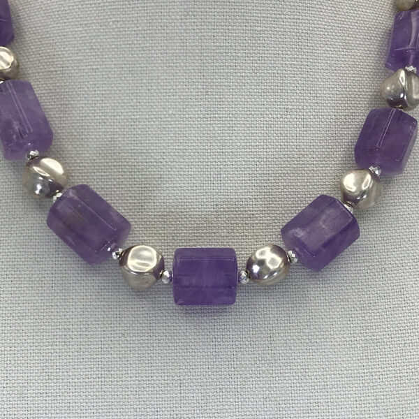 A necklace with purple beads and silver balls.