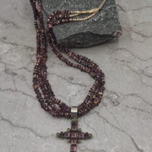 A cross necklace is sitting on the ground.